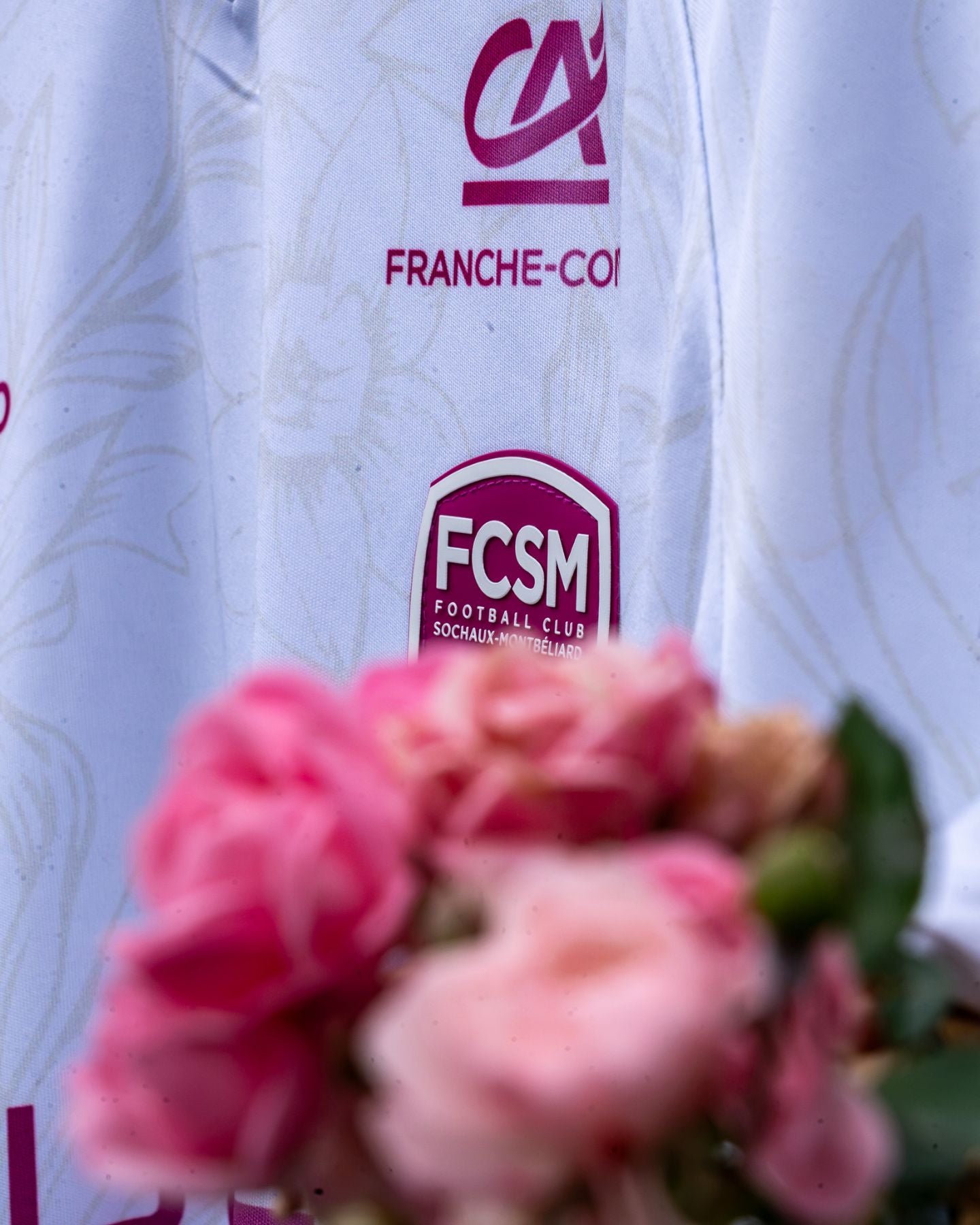 Détail du blason FCSM et du motif jonquille, roses au premier plan